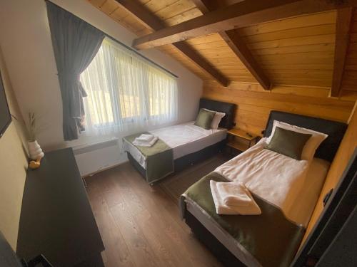 Cette petite chambre comprend 2 lits et une fenêtre. dans l'établissement HillVill, à Govedartsi