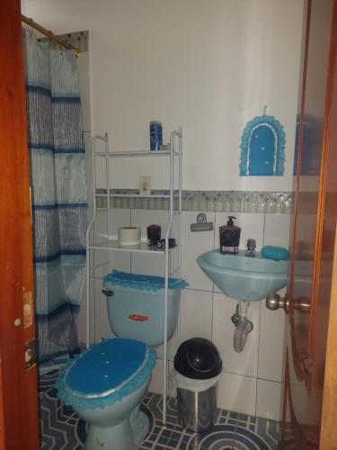 La salle de bains est pourvue de toilettes bleues et d'un lavabo. dans l'établissement C.C. Habitaciones, à Puerto Baquerizo Moreno