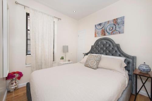 1 dormitorio con 1 cama grande con colcha blanca en 3BR in Amsterdam Ave!, en Nueva York