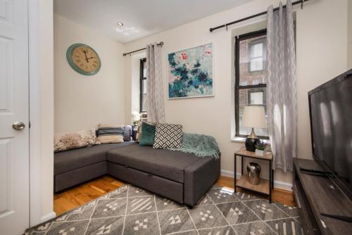 a living room with a couch and a clock on the wall at 3BR in Amsterdam Ave! in New York