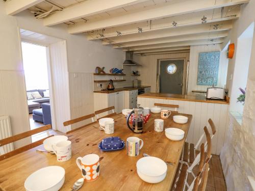 a kitchen with a wooden table with plates and mugs at Tan y Craig in Haverfordwest