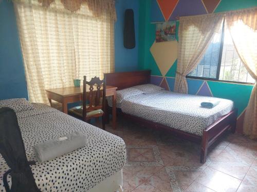a room with two beds and a table and a desk at C.C. Habitaciones in Puerto Baquerizo Moreno