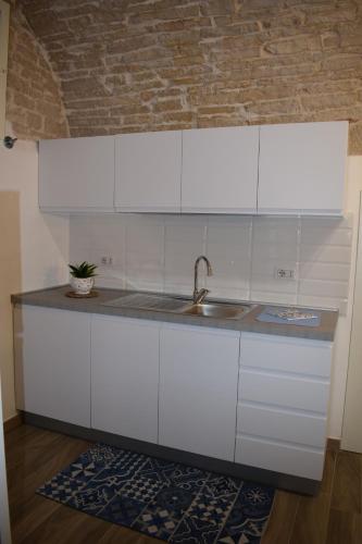 eine Küche mit weißen Schränken und einem Waschbecken in der Unterkunft FA.RÒ. DIMORA in Ruvo di Puglia