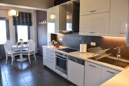 a kitchen with white cabinets and a table with chairs at Sunlight Residence in Kalo Chorio