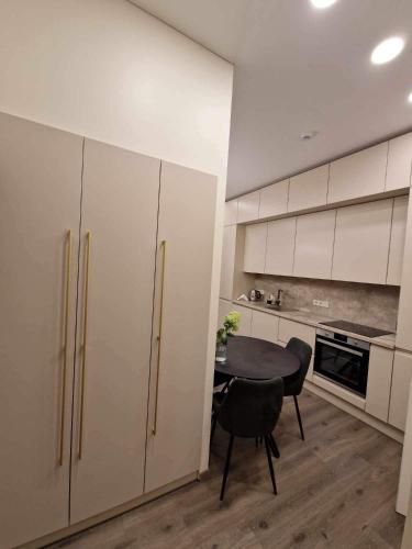 a kitchen with white cabinets and a table and chairs at Centro apartamentai in Panevėžys