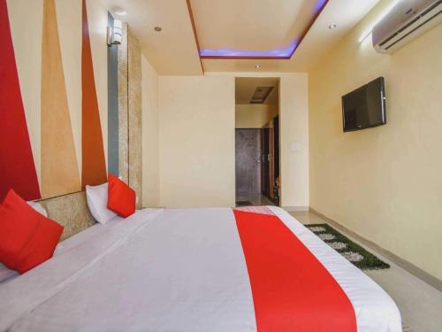 - une chambre avec un lit doté d'oreillers rouges et une télévision dans l'établissement 7R Resort, à Jaipur