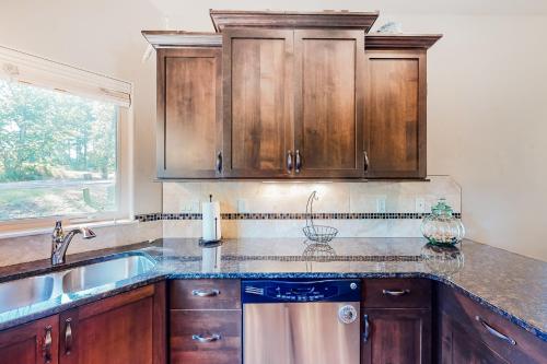 a kitchen with wooden cabinets and a sink and a window at Cedar Point Hideaway in Columbia Falls