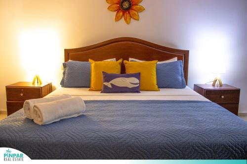 ein Schlafzimmer mit einem großen Bett mit gelben und blauen Kissen in der Unterkunft Pool Terrace, Deluxe E1, Close to Beach, 2Br, 2Bt in Punta Cana