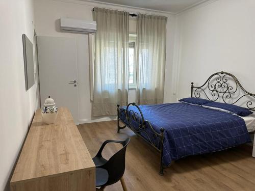 um quarto com uma cama azul e uma mesa de madeira em CasaTua em Catânia