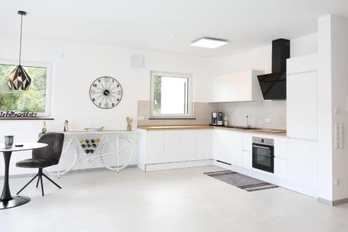 a kitchen with white cabinets and a table and a clock at MV Römervilla, Lofts & Penthouses mit traumhaftem Moselpanoramablick und Sauna in Treis-Karden