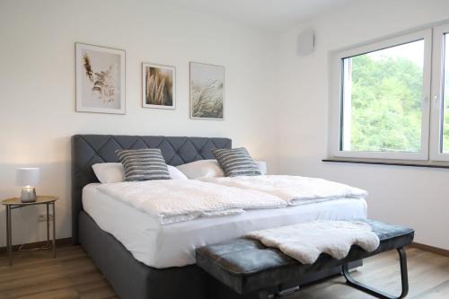 een groot bed in een witte kamer met een raam bij MV Römervilla, Lofts & Penthouses mit traumhaftem Moselpanoramablick und Sauna in Treis-Karden