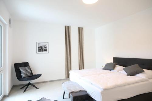 a bedroom with a bed and a black chair at MV Römervilla, Lofts & Penthouses mit traumhaftem Moselpanoramablick und Sauna in Treis-Karden