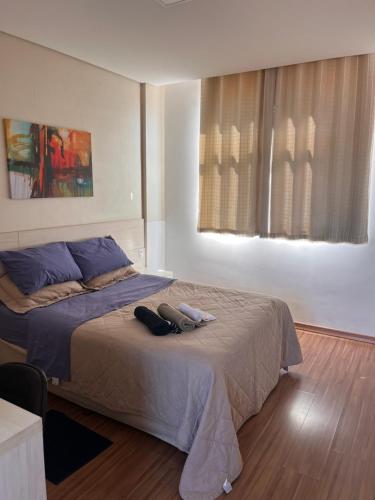a bedroom with a bed with two shoes on it at Suíte Leshalles 311 - no Paris Residencial Service in Lagoa Santa
