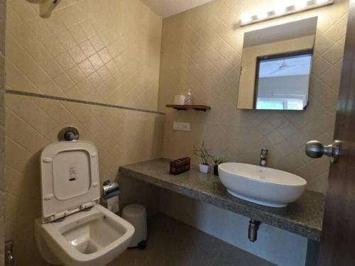 a bathroom with a sink and a toilet and a mirror at Ripples:Pool facing/RiverView/7 mins to Coco Beach in Nerul