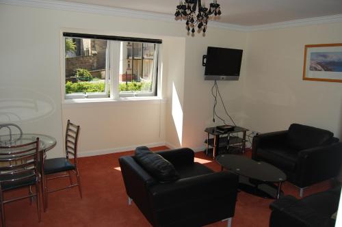 sala de estar con muebles negros y ventana en Anne House, Royal Mile, en Edimburgo