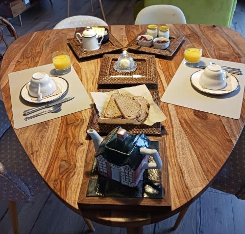 uma mesa de madeira com um bule de chá e um prato de comida em chambre d'hôte proche mer em Yvias