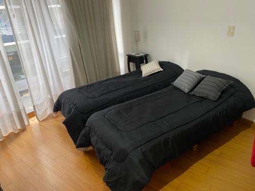 a bedroom with two large beds with black comforters at Monoambiente en Cañitas in Buenos Aires
