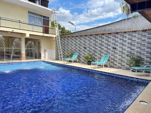 una piscina con 2 sillas azules junto a un edificio en Casa Hotel Estelar, en Villavieja