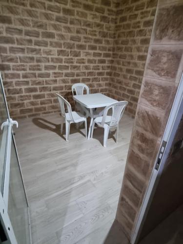 une table et des chaises blanches devant un mur de briques dans l'établissement Appart tranquille au centre de marrakech, à Marrakech