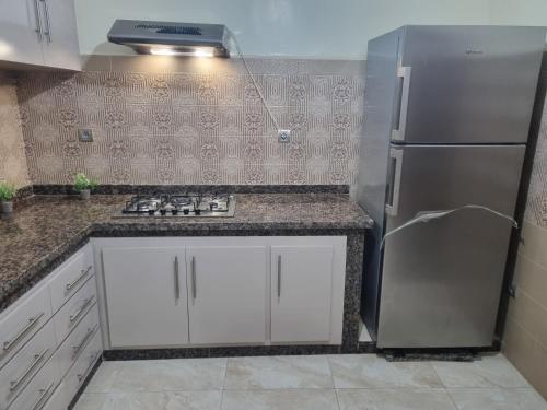 a kitchen with a stainless steel refrigerator and white cabinets at Appart tranquille au centre de marrakech in Marrakesh