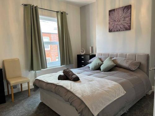 a bedroom with a bed with a chair and a window at Spacious 2-Bedroom House In Stockton Heath With Free WiFi By Amazing Spaces Relocations Ltd in Warrington