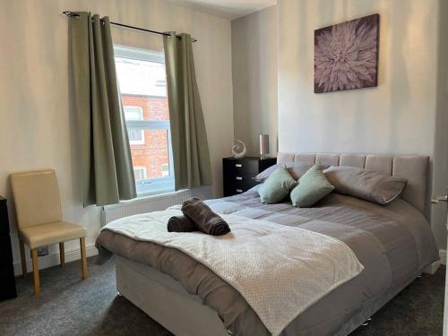 沃灵顿Spacious 2-Bedroom House In Stockton Heath With Free WiFi By Amazing Spaces Relocations Ltd的一间卧室配有一张带椅子的床和一扇窗户