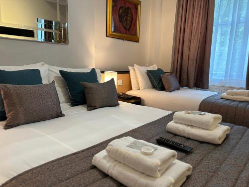 a hotel room with two beds with towels on them at Tudor Court Hotel in London