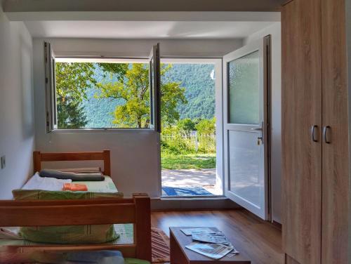ein Schlafzimmer mit einem Fenster, einem Bett und einer Tür in der Unterkunft Guesthouse Mirkovic in Plužine