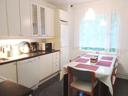 cocina con mesa y cocina con armarios blancos en Great location In Helsinki, en Helsinki