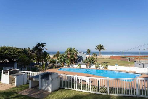 a swimming pool with a white fence and the beach at Seaside Getaway in Margate