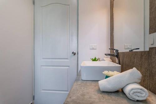 La salle de bains est pourvue d'un lavabo et d'un lavabo blancs. dans l'établissement Casa Alegria BY Sandy Powerful, à Tulum