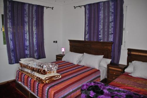 a bedroom with two beds and purple curtains at Ferme Dar Aicha green Bellouta in Bellouta