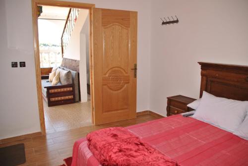 a bedroom with a bed with a red blanket at Ferme Dar Aicha green Bellouta in Bellouta
