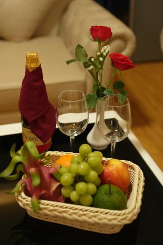 a basket of fruit with wine glasses and roses at Pleiku & Em Hotel by Gia Lai Tourist in Pleiku