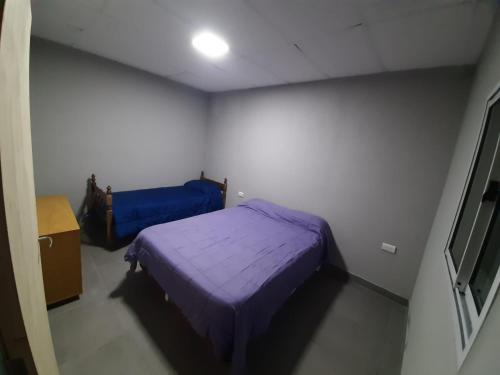 una piccola camera con letto viola e TV di Departamento Belen a Santa Rosa