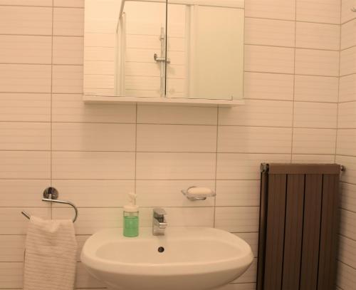 a white bathroom with a sink and a cabinet at Apartments Fink in Portorož