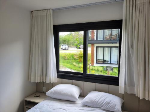 a bed with two pillows in front of a window at Praia do Forte - Villa do Lago in Praia do Forte