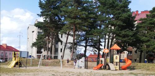 a playground in a park with orange slides and trees at M2 Art in Giżycko