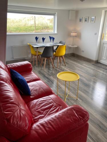 uma sala de estar com um sofá de couro vermelho e uma mesa em Anchor’s Away em Letterkenny
