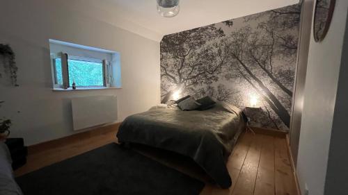 Gîte Chantoiseaux في Belmont-sur-Buttant: غرفة نوم بسرير وجدار بجدار شجرة جدارية