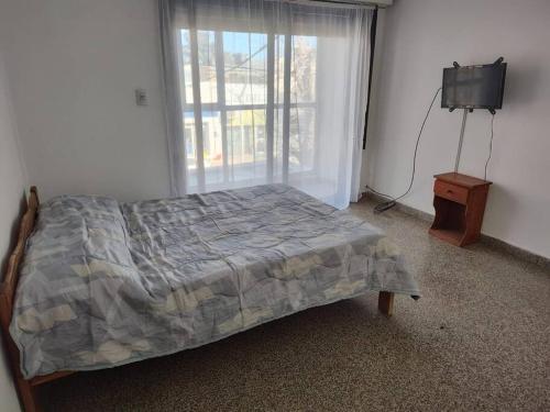 a bedroom with a bed and a tv and a window at Depto en el centro de General Roca in General Roca