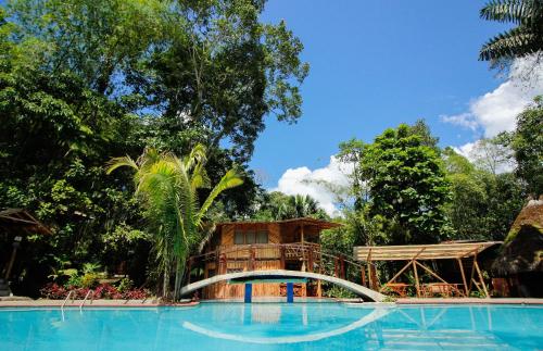 a resort with a large swimming pool with a tree house at Hosteria Flor de Canela in Puyo