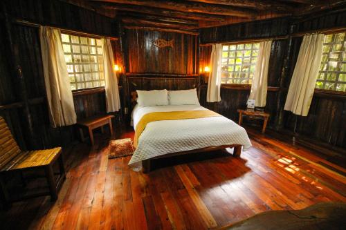 a bedroom with a bed with wooden floors and windows at Hosteria Flor de Canela in Puyo
