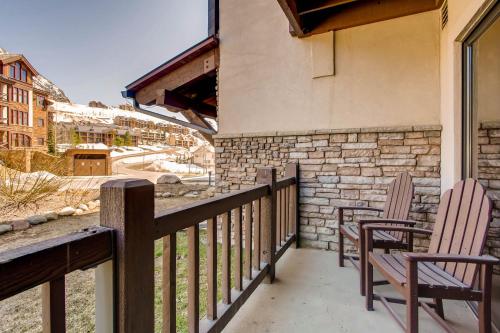 a balcony with two chairs and a stone wall at The Plaza Condominiums by Crested Butte Mountain Resort in Mount Crested Butte
