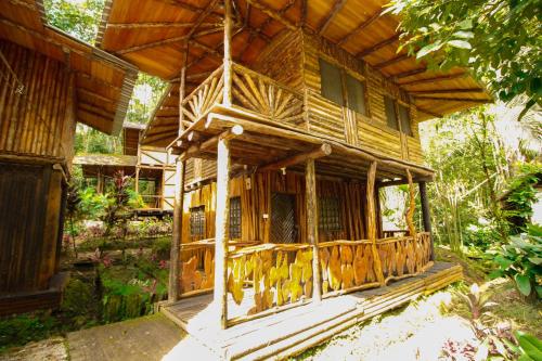 a wooden house with a porch in a forest at Hosteria Flor de Canela in Puyo