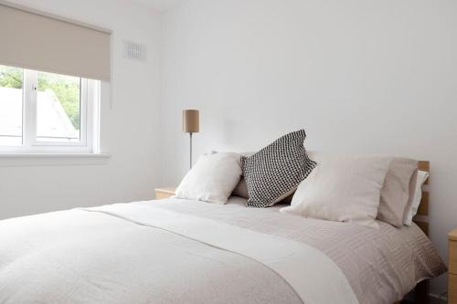 a white bedroom with a bed with white sheets and pillows at Two Bedroom Country Cottage With Parking in Musselburgh