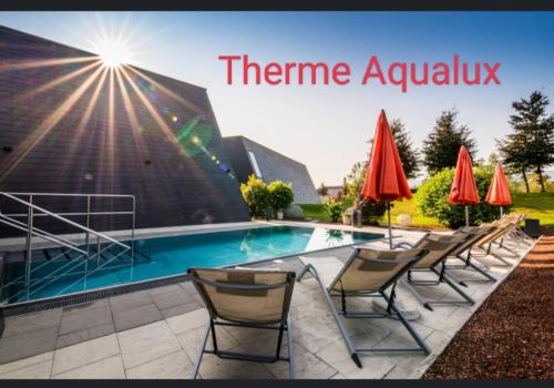 a pool with chairs and umbrellas in front of a building at Holiday Apartment Murtal in Judenburg