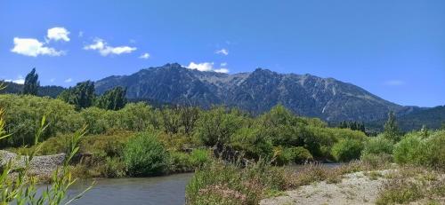 une rivière avec des arbres et des montagnes en arrière-plan dans l'établissement Hostería de Montaña Las Pataguas, à El Hoyo
