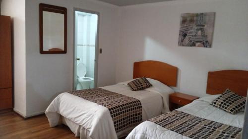 una camera d'albergo con due letti e uno specchio di Hotel El Gourmet a La Calera