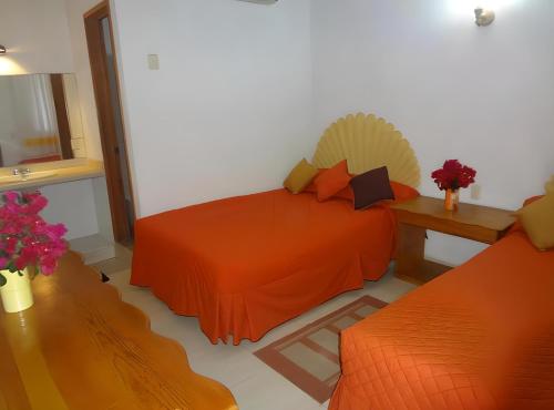 a bedroom with an orange bed and a table at Hotel Victoria in Zihuatanejo